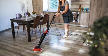 A person uses a steam mop to clean the floor