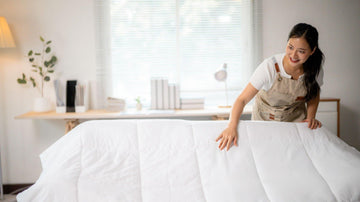 Person vacuuming a mattress with cleaning supplies showing dust removal for healthier sleep