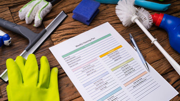 Person organizing cleaning schedule with planner, calendar and cleaning supplies showing task management